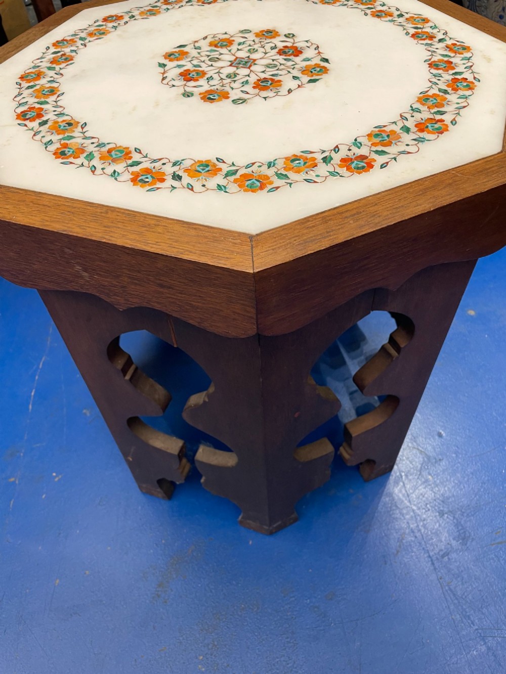 An octagonal wooden side table featuring a white marble top with floral stone inlay and a pierced carved wooden base. View IV