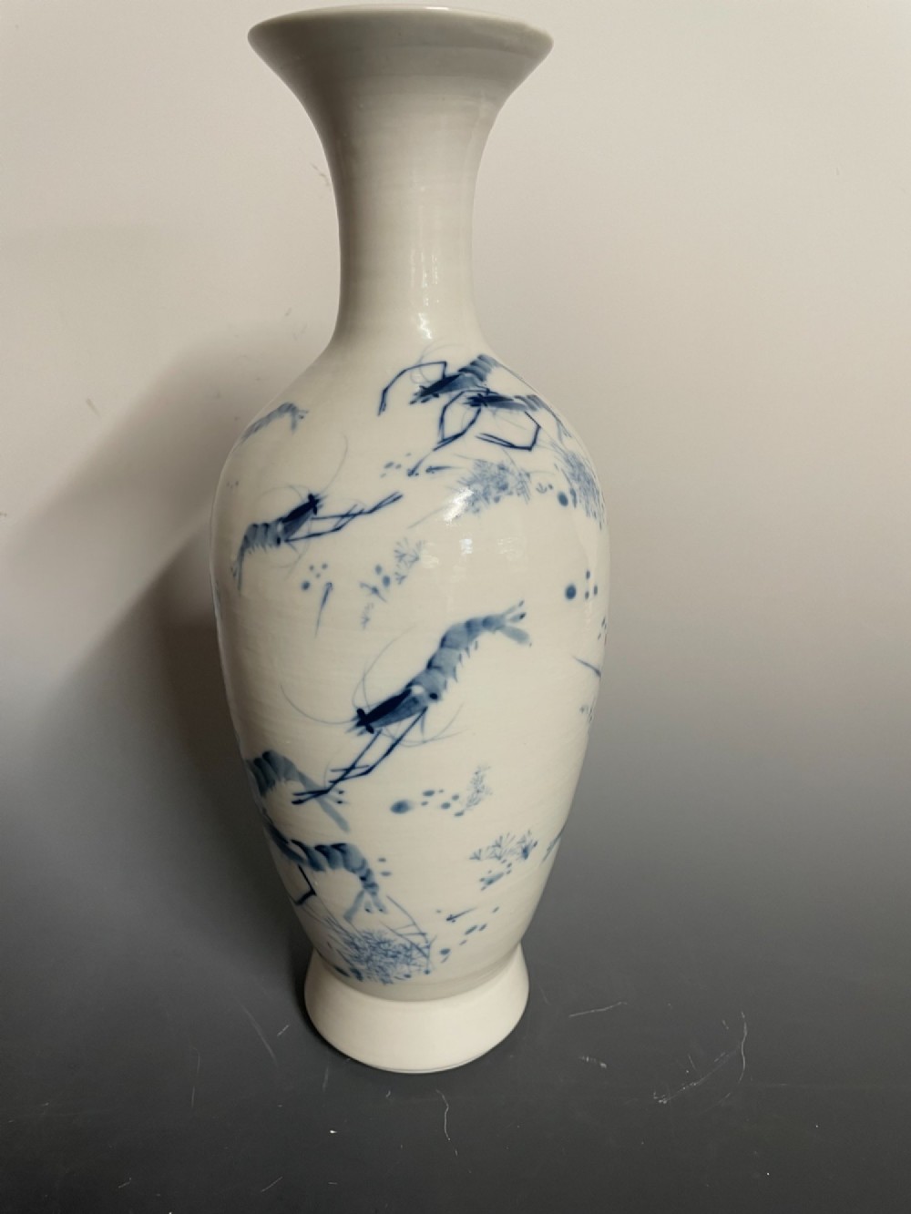 A tall white porcelain vase with a flared rim, featuring hand-painted cobalt blue shrimp motifs around the body. View II