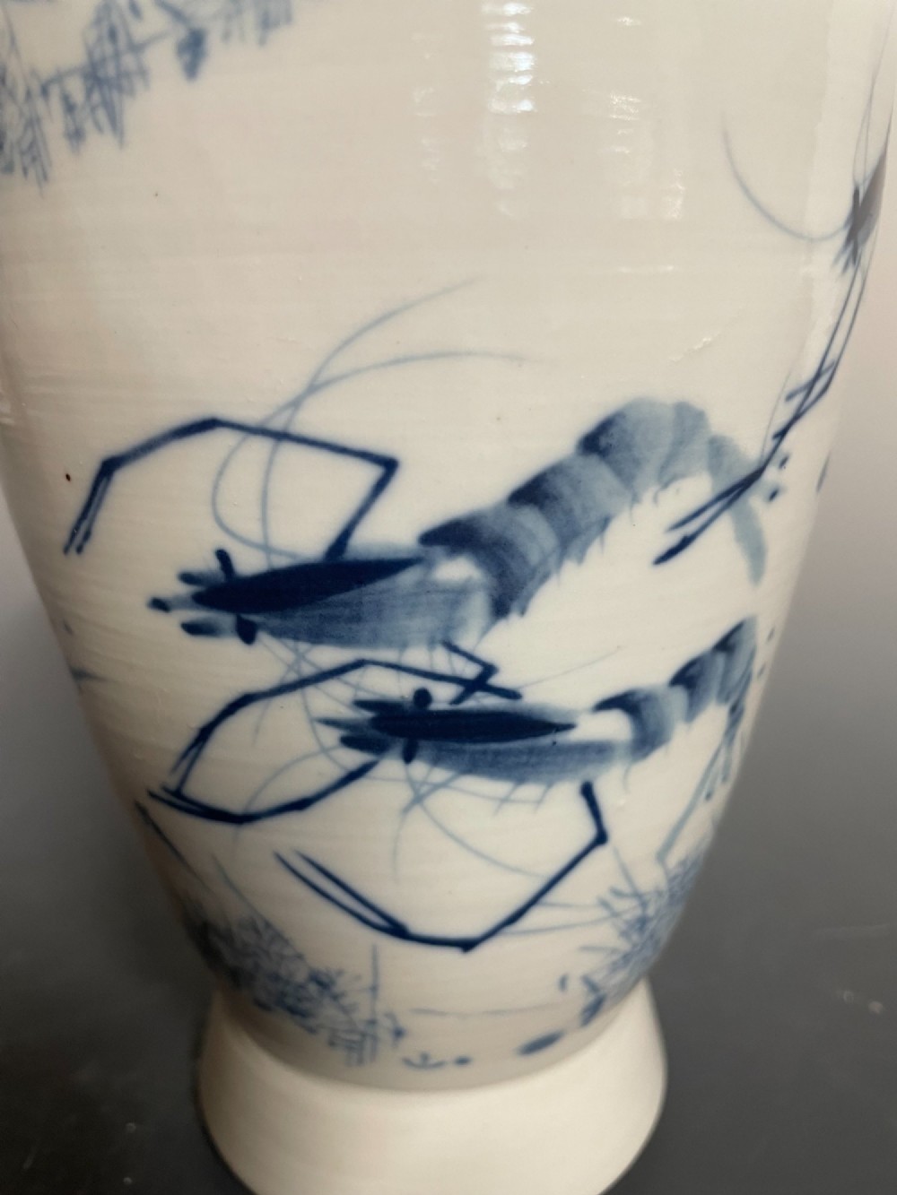 A tall white porcelain vase with a flared rim, featuring hand-painted cobalt blue shrimp motifs around the body. View VI