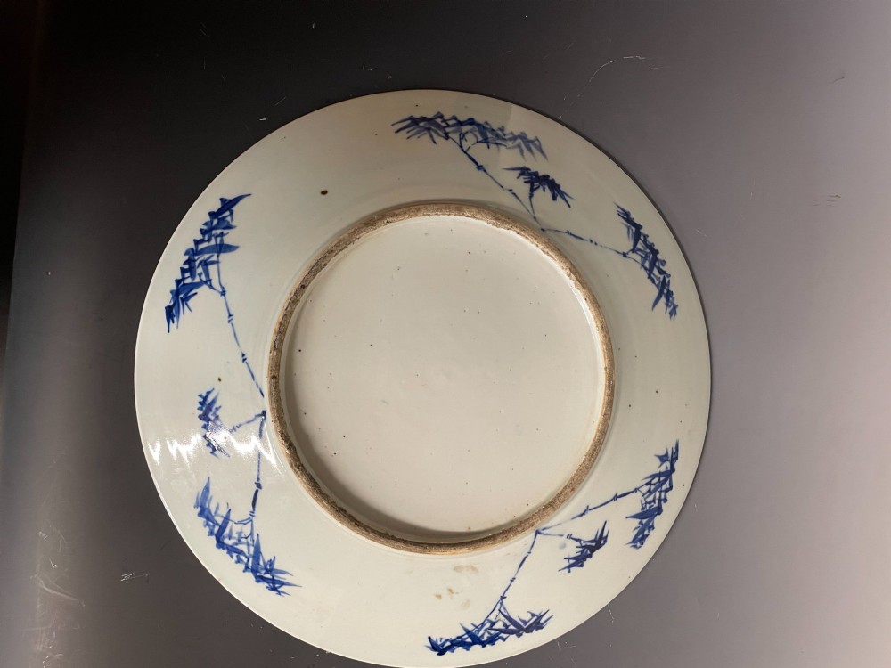 A circular Chinese porcelain plate decorated with underglaze cobalt blue figures beneath a pine tree within floral and geometric patterned borders. View III