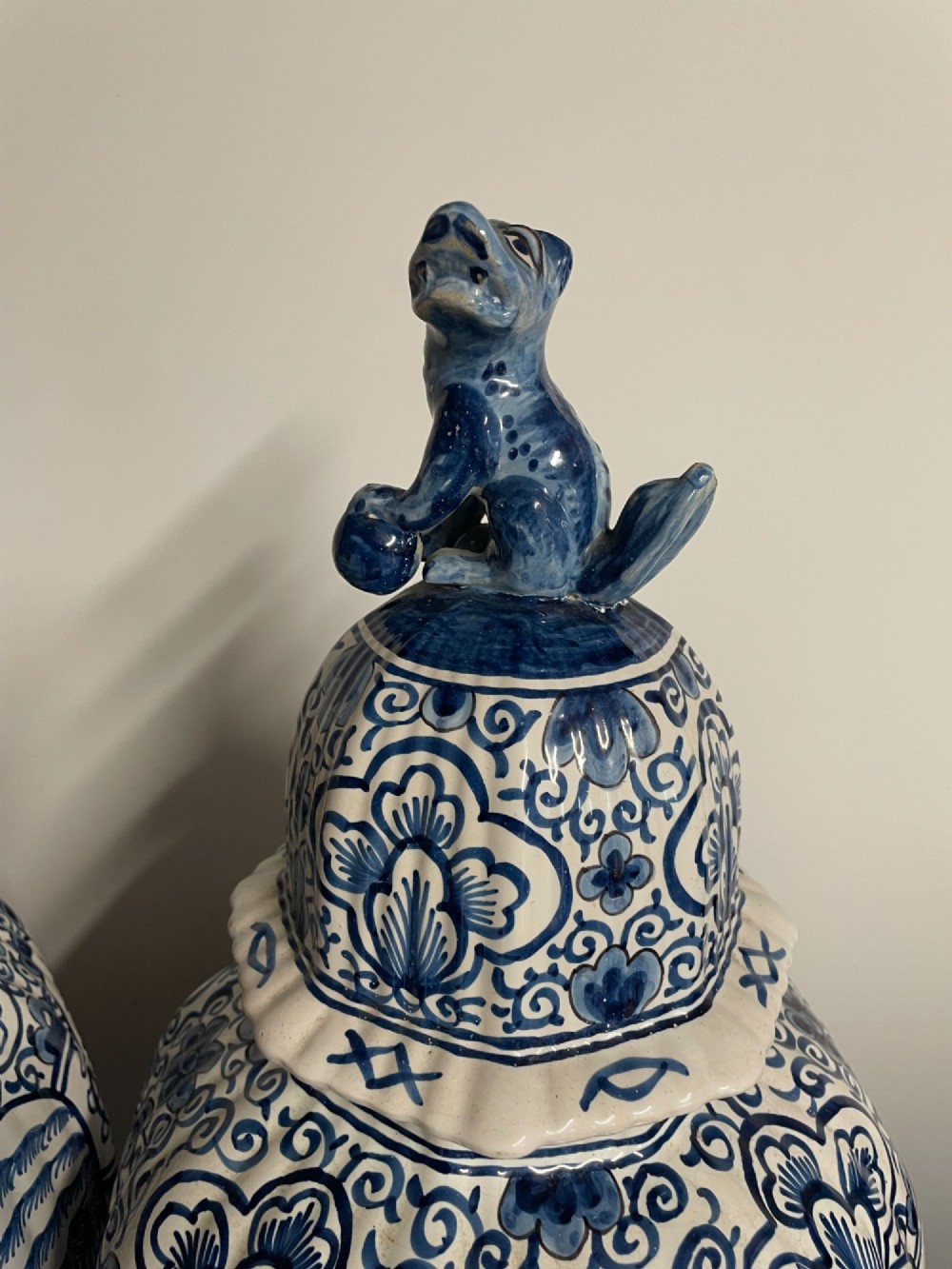 A pair of blue and white tin-glazed earthenware ribbed jars with lidded covers topped with foo dog finials, decorated with hand-painted chinoiserie scenes. View II