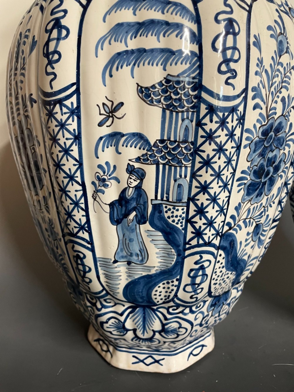 A pair of blue and white tin-glazed earthenware ribbed jars with lidded covers topped with foo dog finials, decorated with hand-painted chinoiserie scenes. View III