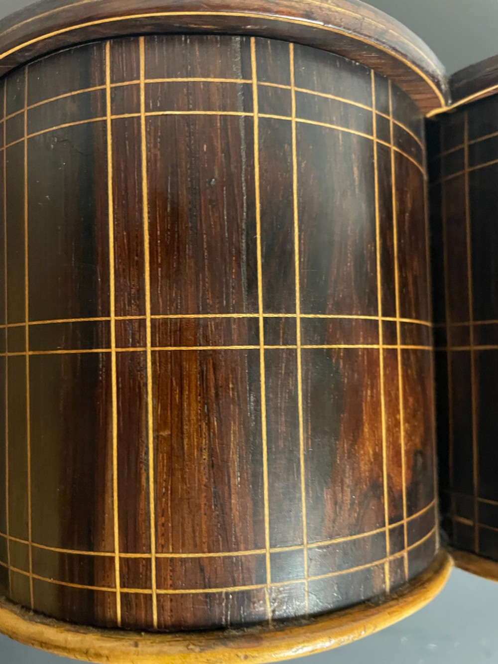 A dark brown wooden double cylindrical tea caddy featuring geometric line inlay and detailed figural marquetry scenes on the lids. View XII