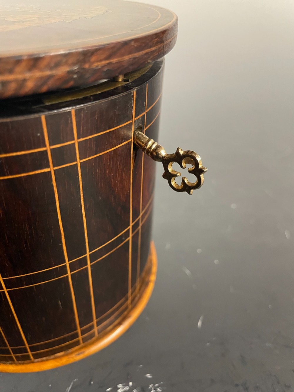 A dark brown wooden double cylindrical tea caddy featuring geometric line inlay and detailed figural marquetry scenes on the lids. View XIII