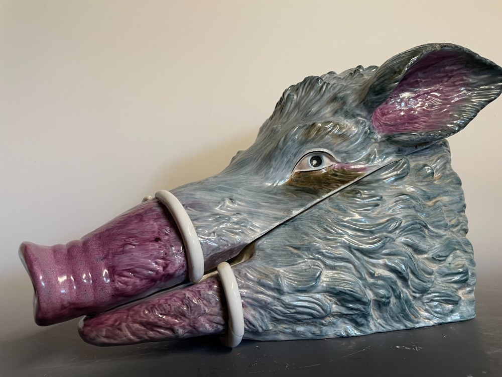 A glazed ceramic majolica tureen sculpted in the shape of a boars head with grey textured fur, pink snout, and white tusks. View III