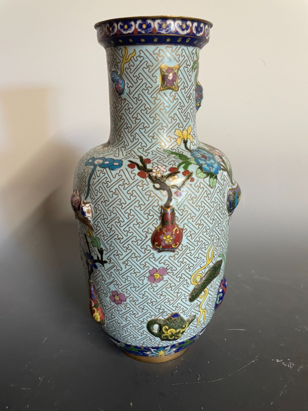A baluster-shaped Chinese cloisonne enamel vase featuring a light blue key fret background embellished with colourful scholars objects and floral motifs. View II