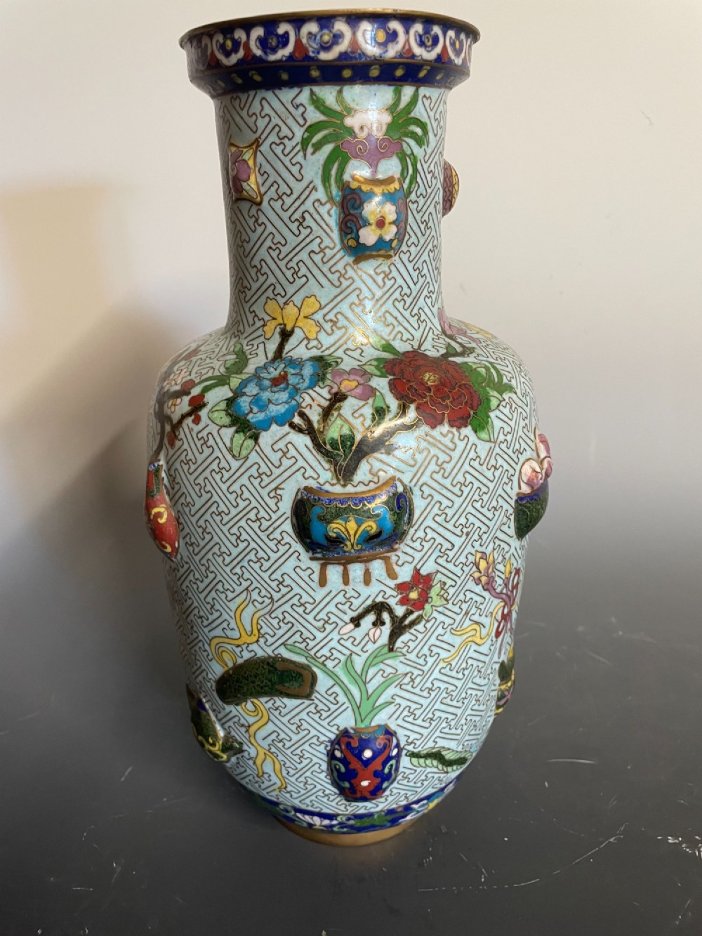A baluster-shaped Chinese cloisonne enamel vase featuring a light blue key fret background embellished with colourful scholars objects and floral motifs. View III