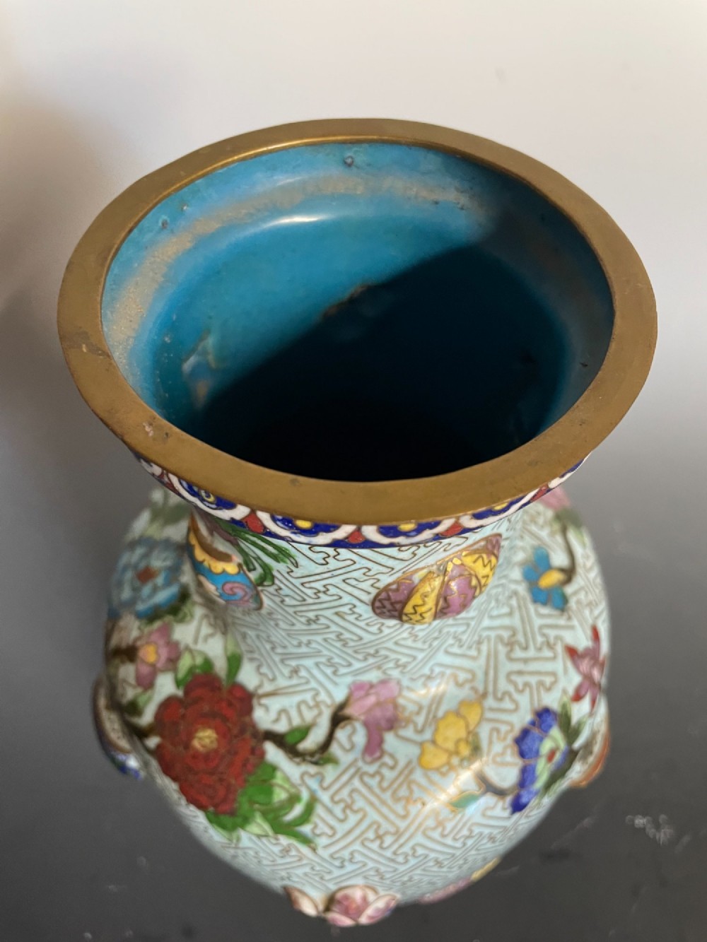A baluster-shaped Chinese cloisonne enamel vase featuring a light blue key fret background embellished with colourful scholars objects and floral motifs. View V
