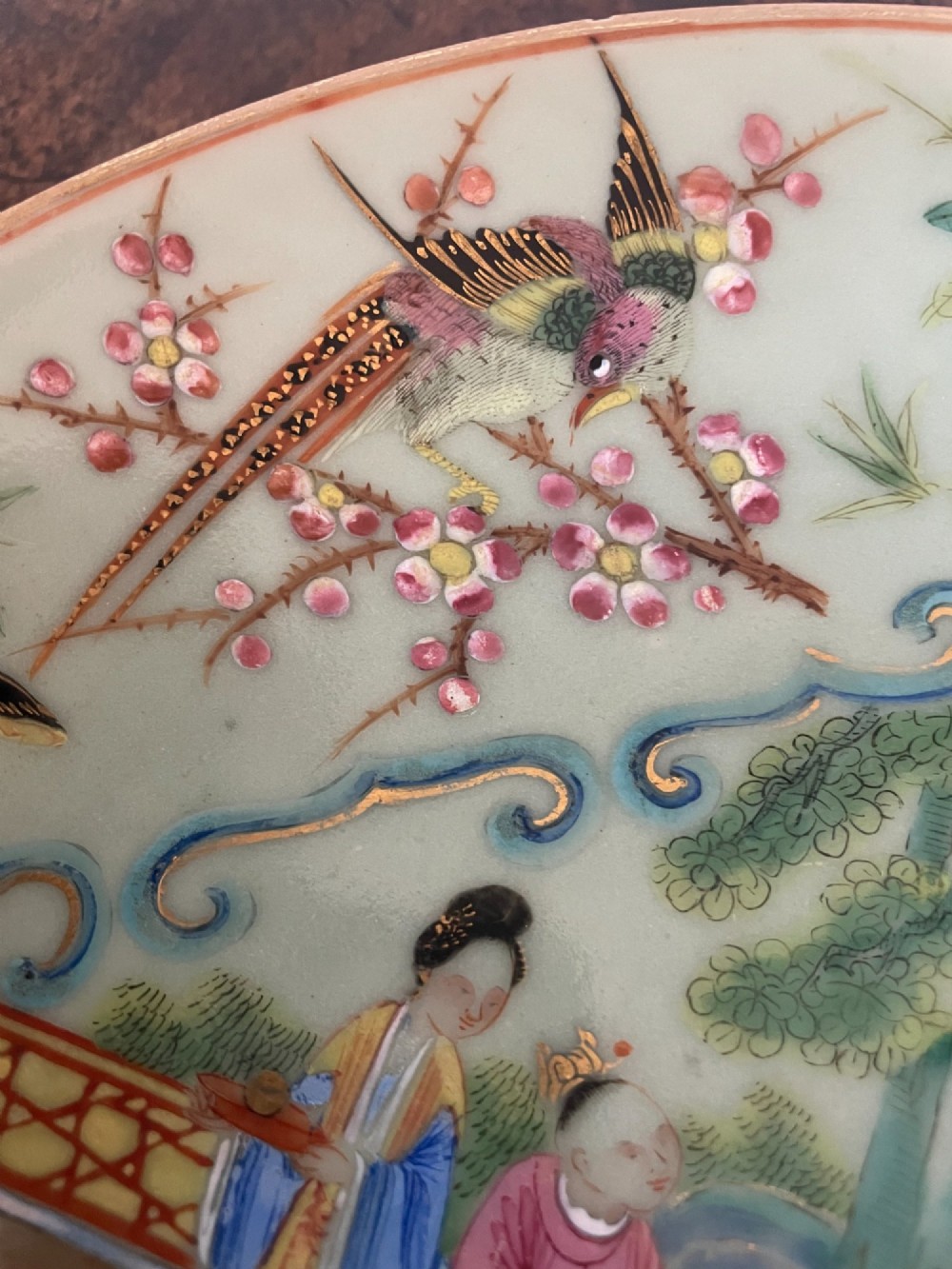 A circular Chinese export celadon porcelain plate hand-painted with a central figurative reserve surrounded by floral motifs, birds, and butterflies in multi-coloured enamels. View III