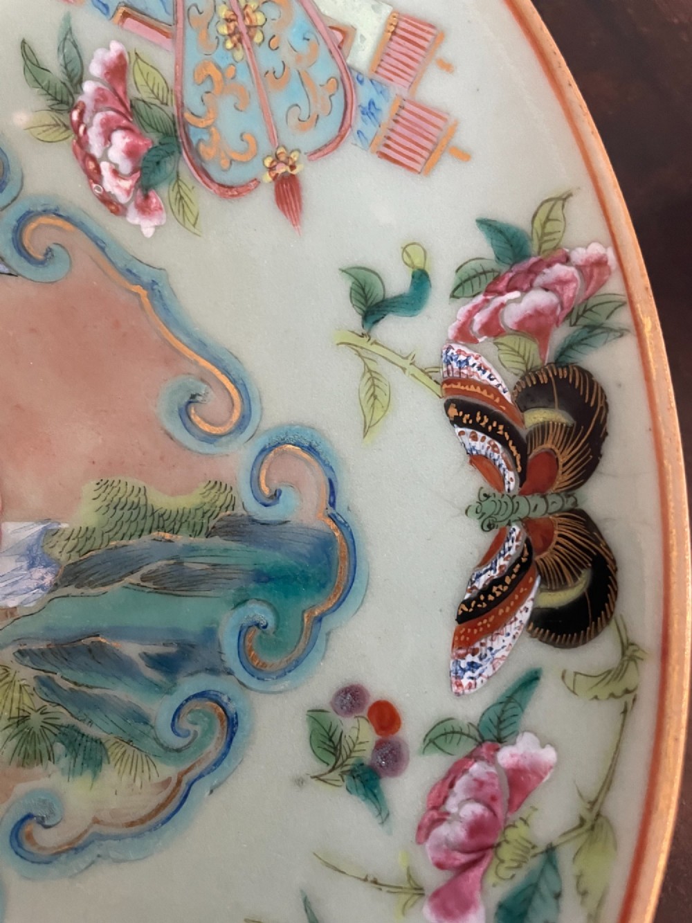 A circular Chinese export celadon porcelain plate hand-painted with a central figurative reserve surrounded by floral motifs, birds, and butterflies in multi-coloured enamels. View IV