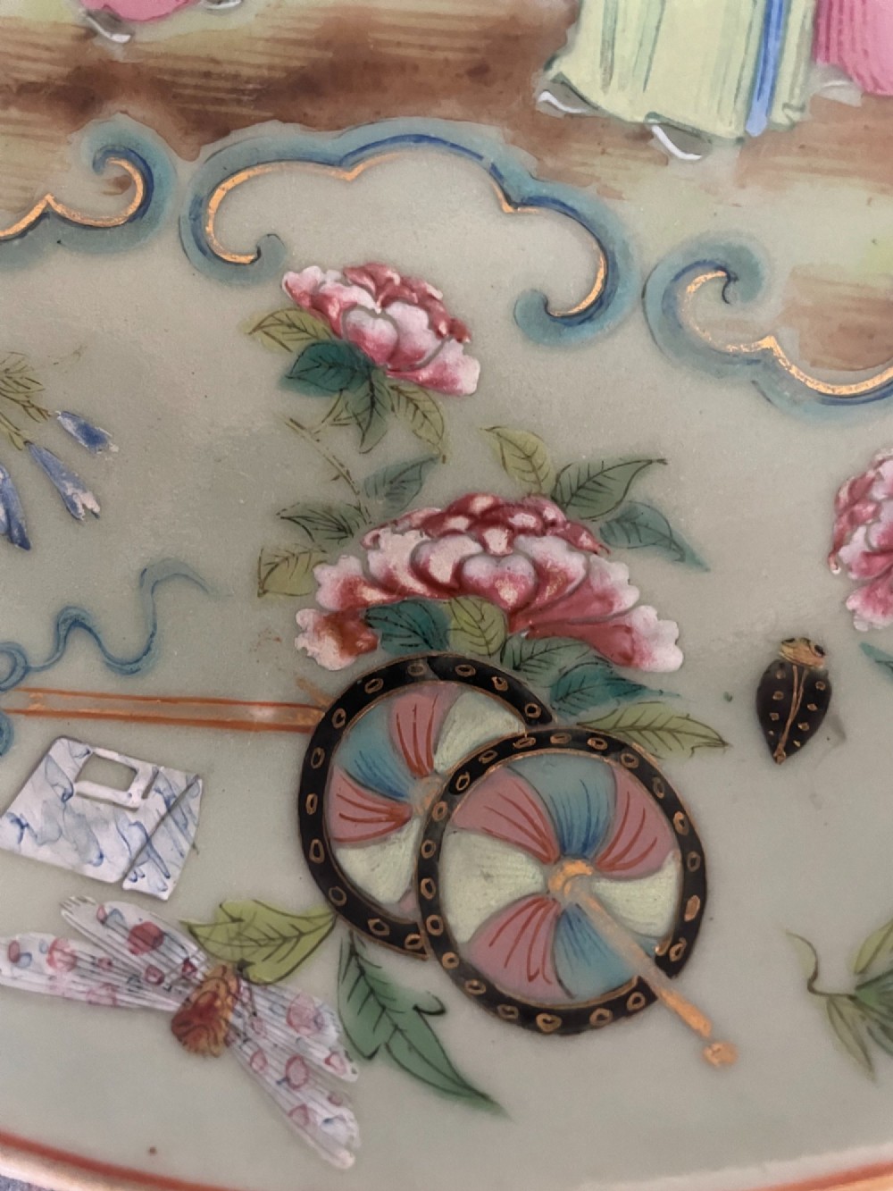 A circular Chinese export celadon porcelain plate hand-painted with a central figurative reserve surrounded by floral motifs, birds, and butterflies in multi-coloured enamels. View V