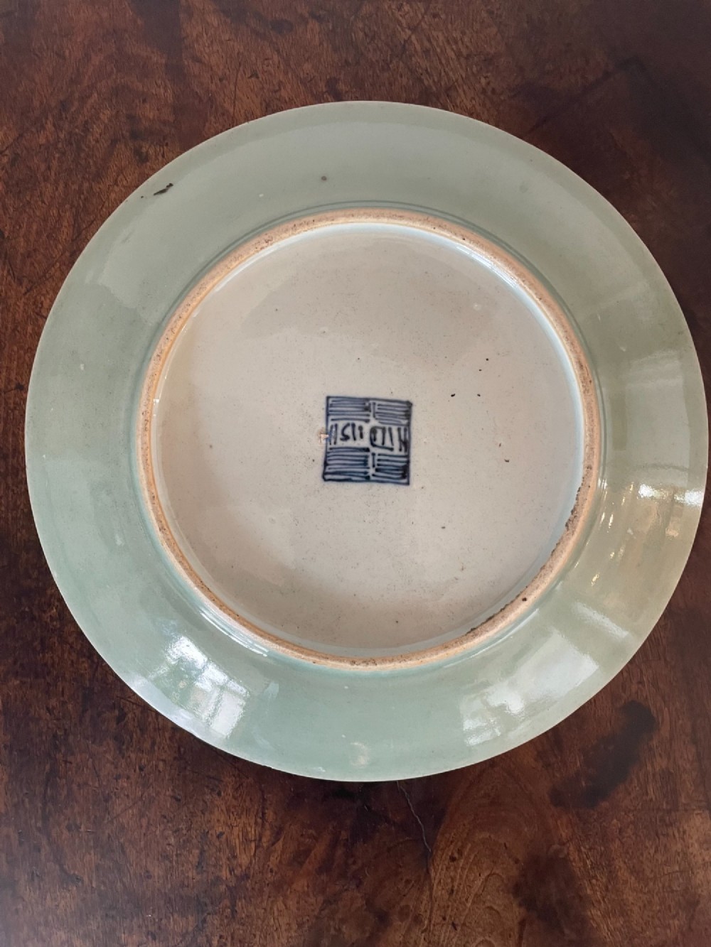 A circular Chinese export celadon porcelain plate hand-painted with a central figurative reserve surrounded by floral motifs, birds, and butterflies in multi-coloured enamels. View VII