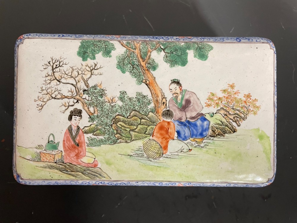 A rectangular Chinese Canton enamel box with rounded corners featuring hand-painted figures in a landscape setting on the lid and floral scrollwork on the side. View II