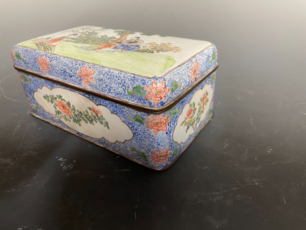 A rectangular Chinese Canton enamel box with rounded corners featuring hand-painted figures in a landscape setting on the lid and floral scrollwork on the side. View III