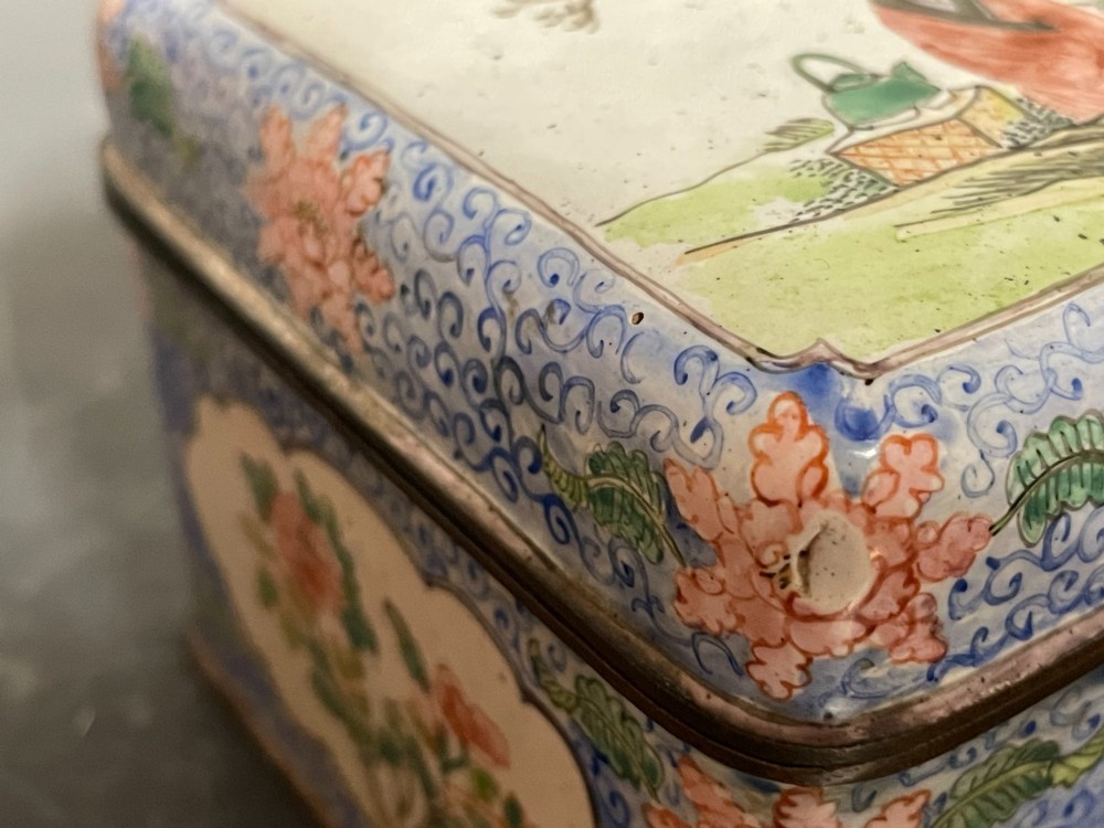 A rectangular Chinese Canton enamel box with rounded corners featuring hand-painted figures in a landscape setting on the lid and floral scrollwork on the side. View V