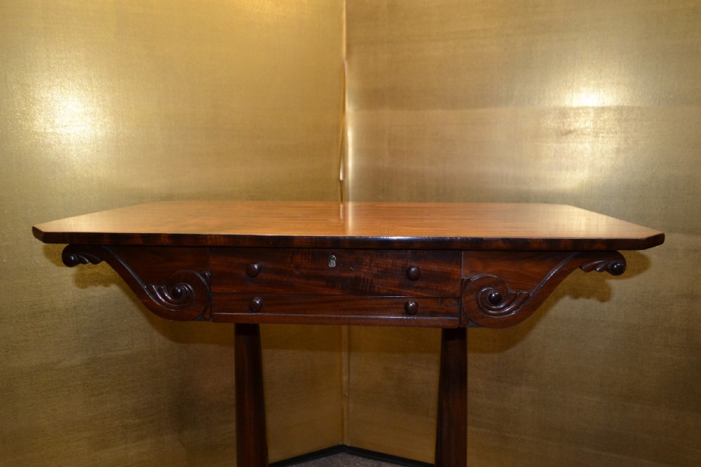 A William IV mahogany side table featuring carved scroll brackets, twin turned column supports, and a shaped plinth base on scroll feet. View II
