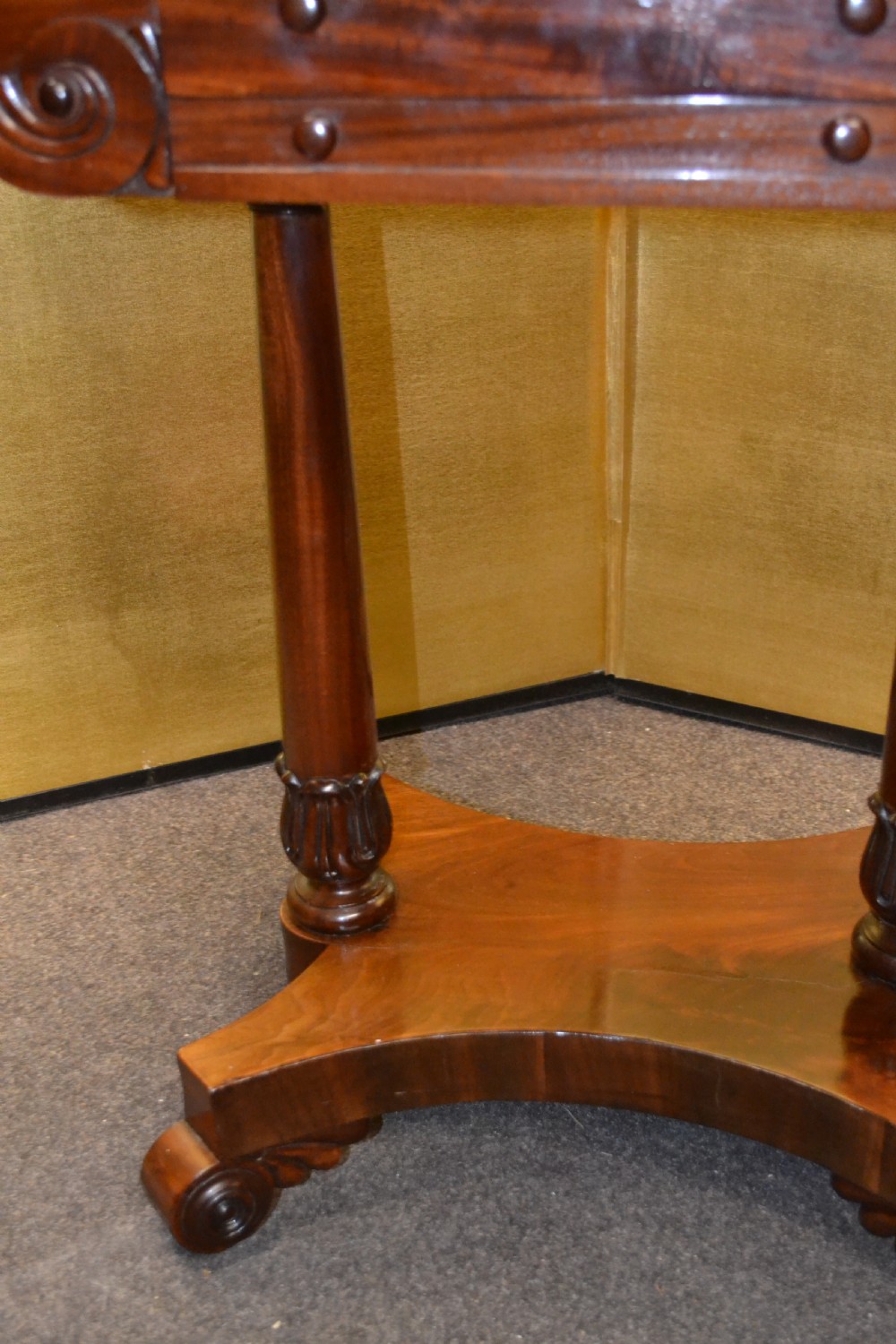 A William IV mahogany side table featuring carved scroll brackets, twin turned column supports, and a shaped plinth base on scroll feet. View III