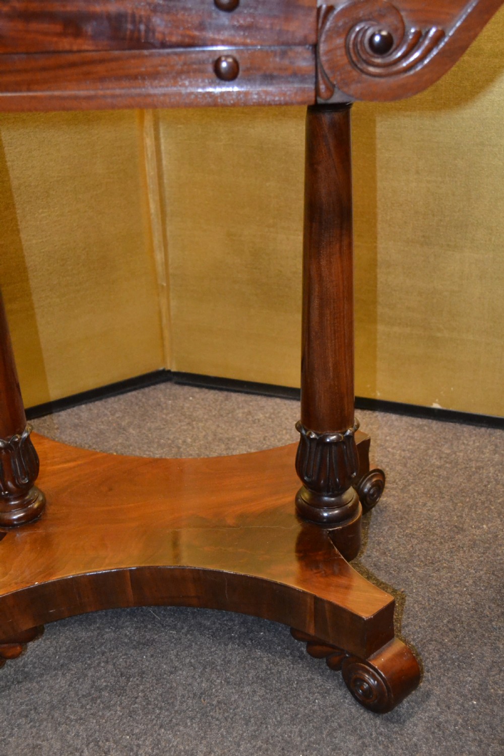 A William IV mahogany side table featuring carved scroll brackets, twin turned column supports, and a shaped plinth base on scroll feet. View IV
