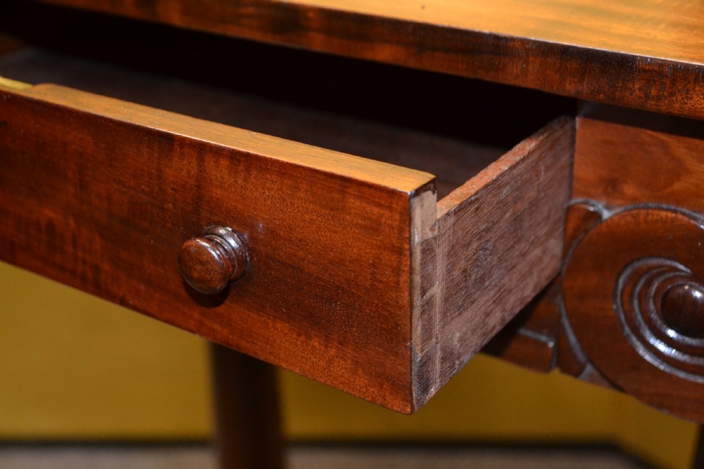 A William IV mahogany side table featuring carved scroll brackets, twin turned column supports, and a shaped plinth base on scroll feet. View V
