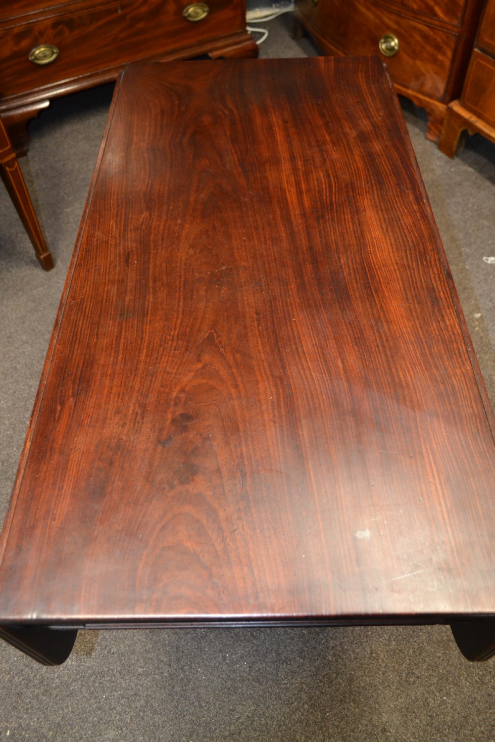 An antique mahogany Pembroke table featuring hinged drop leaves, supported by a central carved pedestal with four splayed legs ending in carved feet. View IV