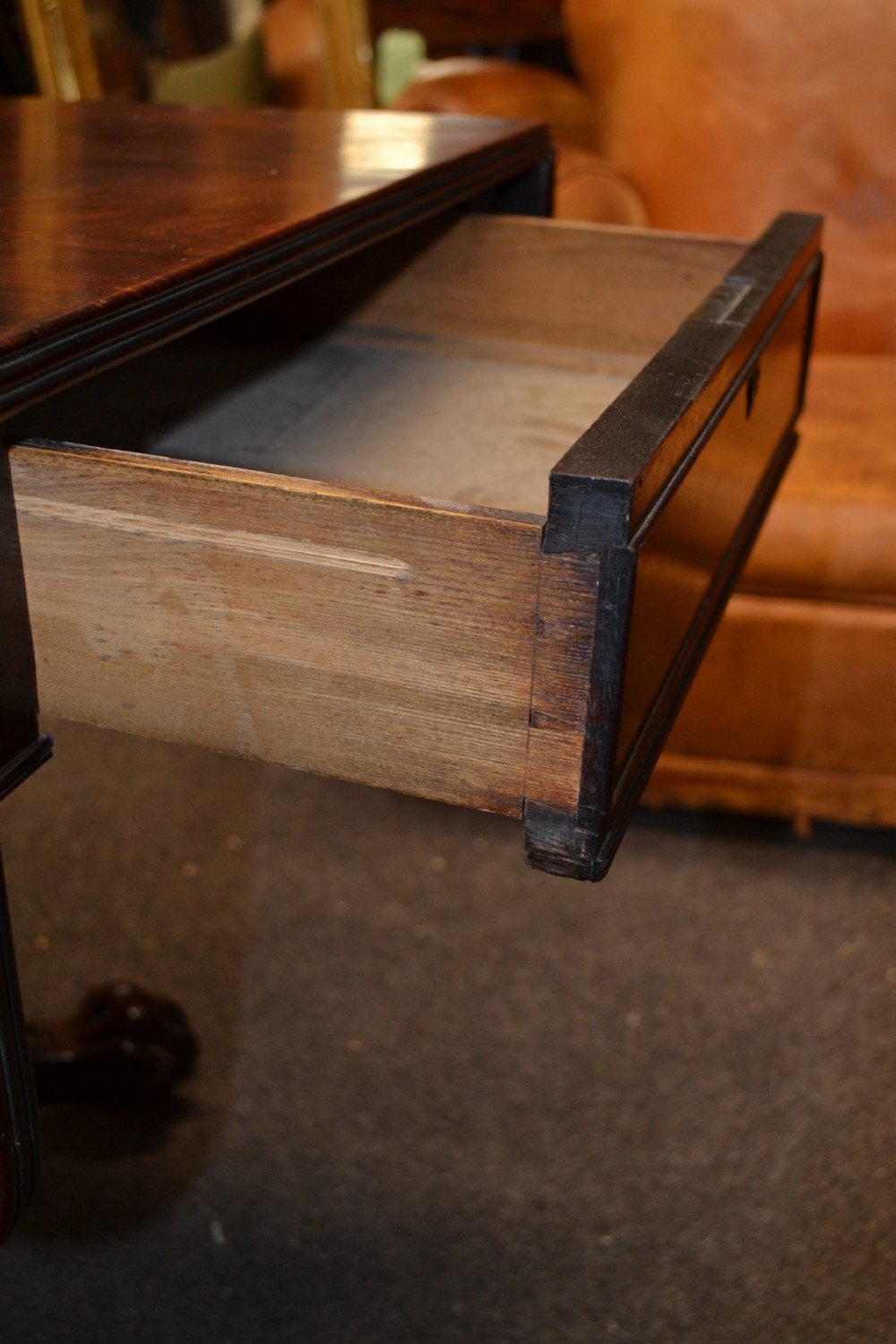An antique mahogany Pembroke table featuring hinged drop leaves, supported by a central carved pedestal with four splayed legs ending in carved feet. View V