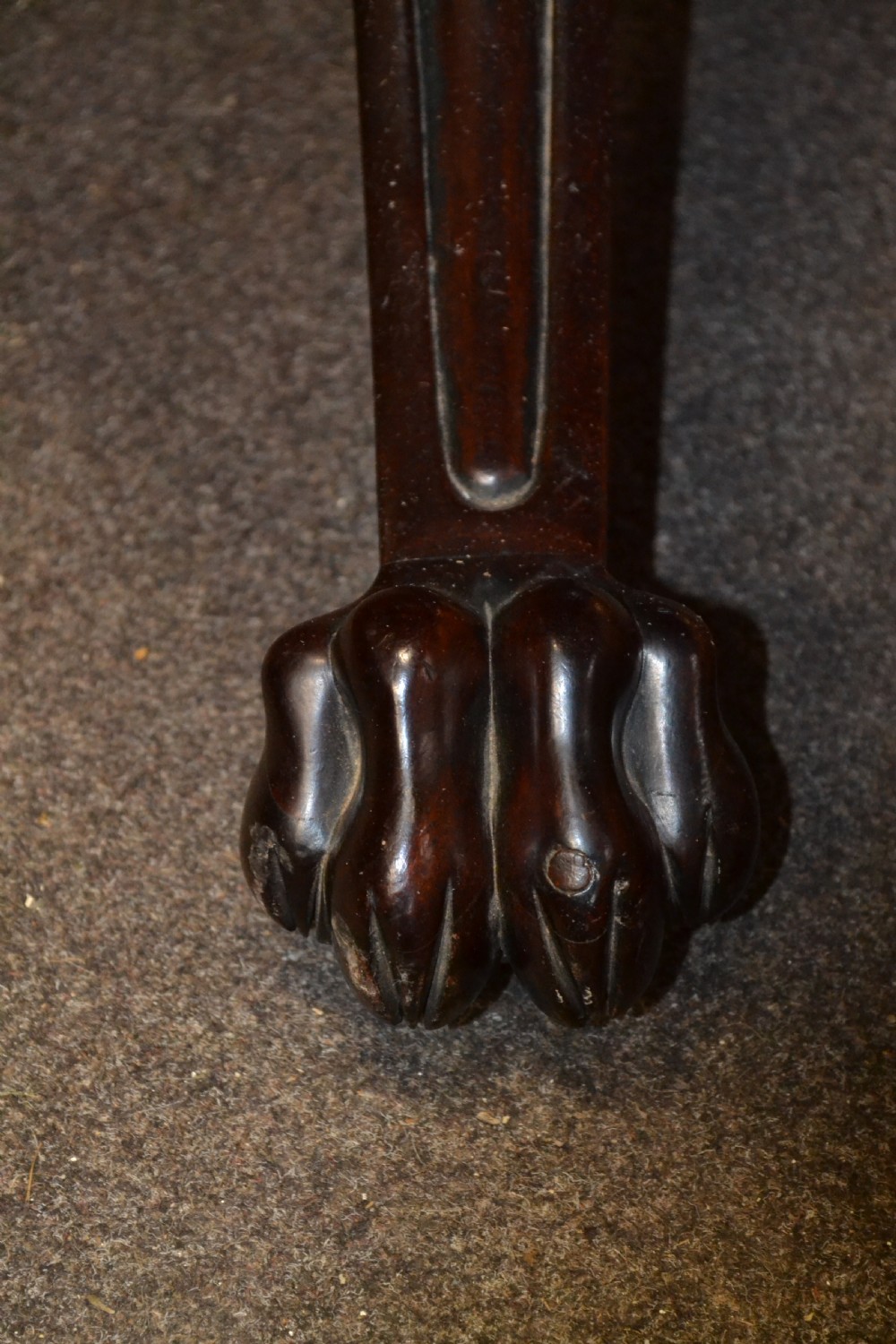 An antique mahogany Pembroke table featuring hinged drop leaves, supported by a central carved pedestal with four splayed legs ending in carved feet. View VI