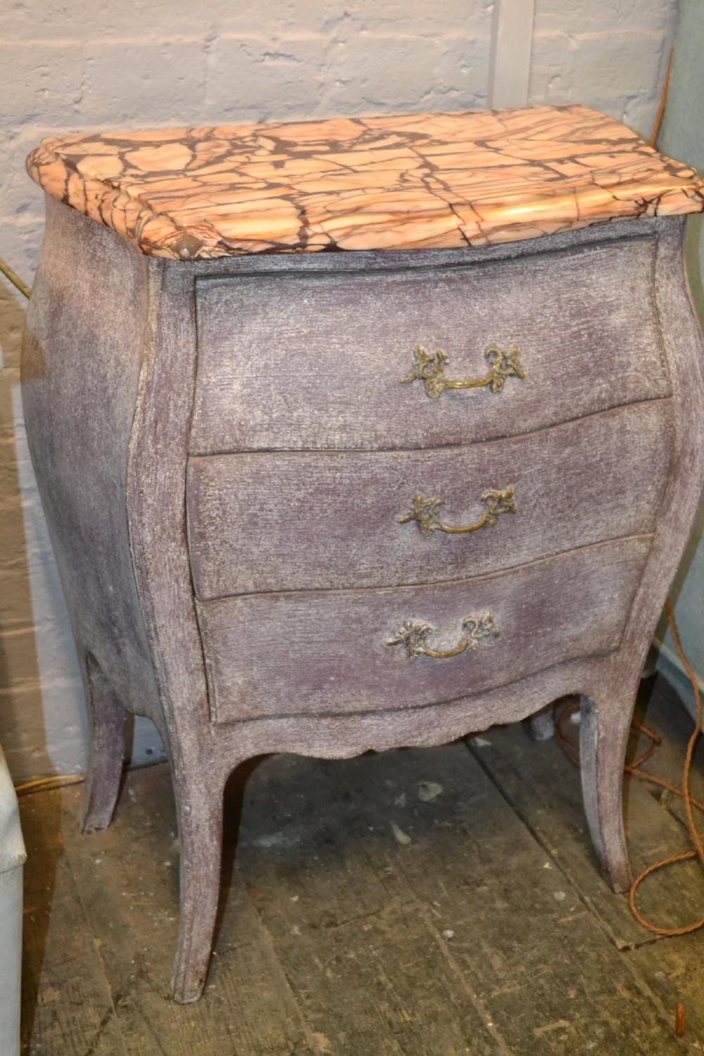 A small French-style three-drawer commode with a distressed grey paint finish, curved cabriole legs, decorative brass handles, and a veined marble top. View III