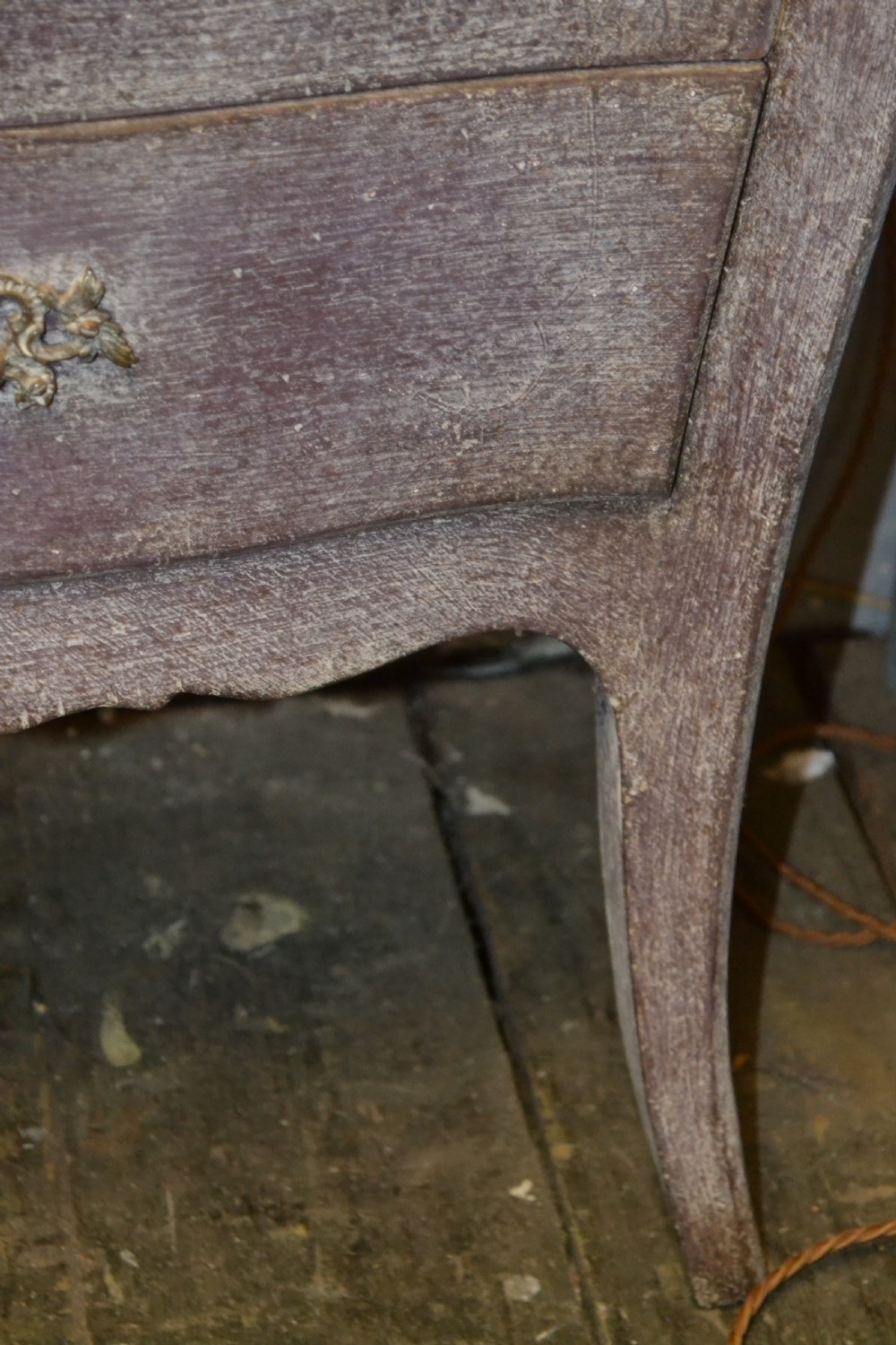A small French-style three-drawer commode with a distressed grey paint finish, curved cabriole legs, decorative brass handles, and a veined marble top. View V