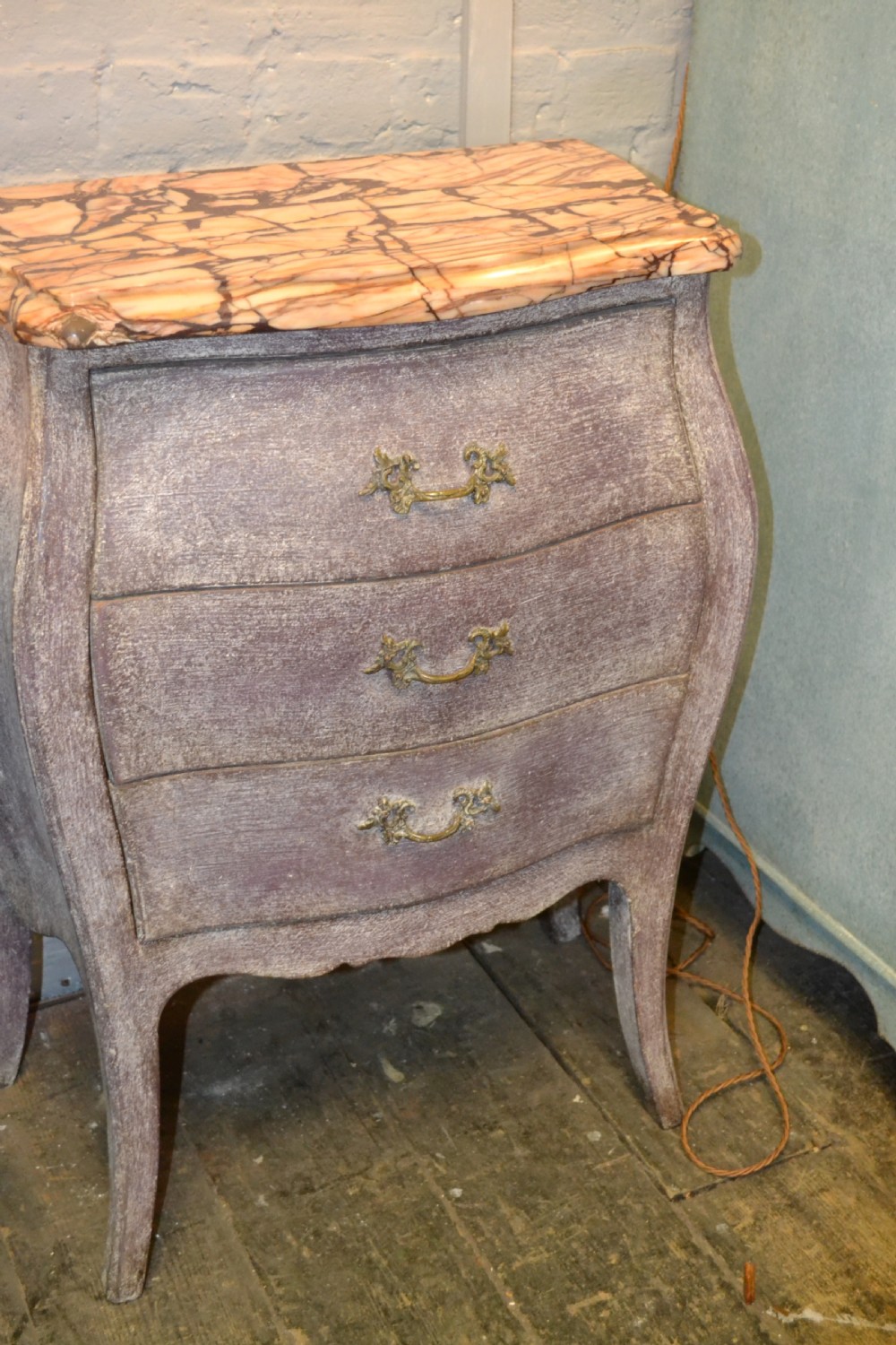 A small French-style three-drawer commode with a distressed grey paint finish, curved cabriole legs, decorative brass handles, and a veined marble top. View IX