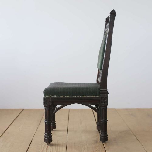 A pair of 19th-century Gothic Revival side chairs crafted from dark carved wood with dark green upholstered seats and backrests featuring pointed arch motifs. View V