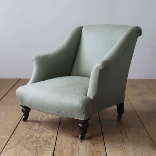 A 19th-century Victorian armchair upholstered in sage green fabric, featuring sloping arms and dark turned wooden front legs with castors. View II
