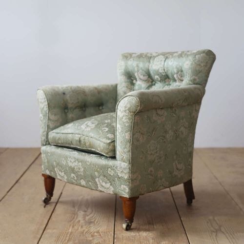 A 19th-century upholstered armchair featuring sage green floral damask fabric, deep button-tufting on the backrest, turned wood front legs, and brass castors. View III