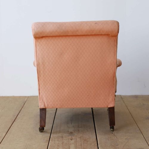 A pair of 19th-century upholstered armchairs in peach woven fabric featuring turned mahogany front legs with brass castors. View V