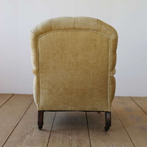 A 19th-century Victorian button-backed open armchair featuring sage green upholstery, turned dark mahogany front legs, and brass castors. View IV