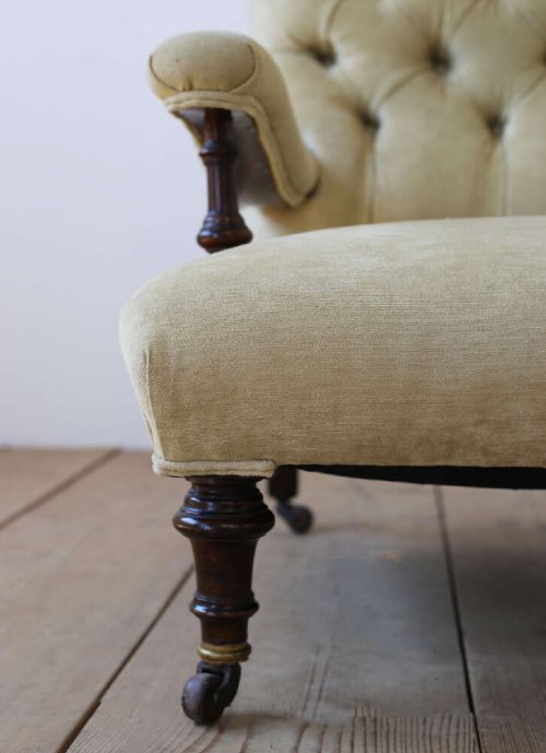 A 19th-century Victorian button-backed open armchair featuring sage green upholstery, turned dark mahogany front legs, and brass castors. View V