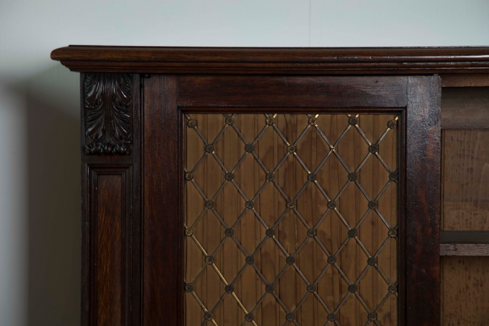 A pair of matching dark mahogany low cabinets featuring double doors with brass diamond wire grilles and carved corner accents. View V