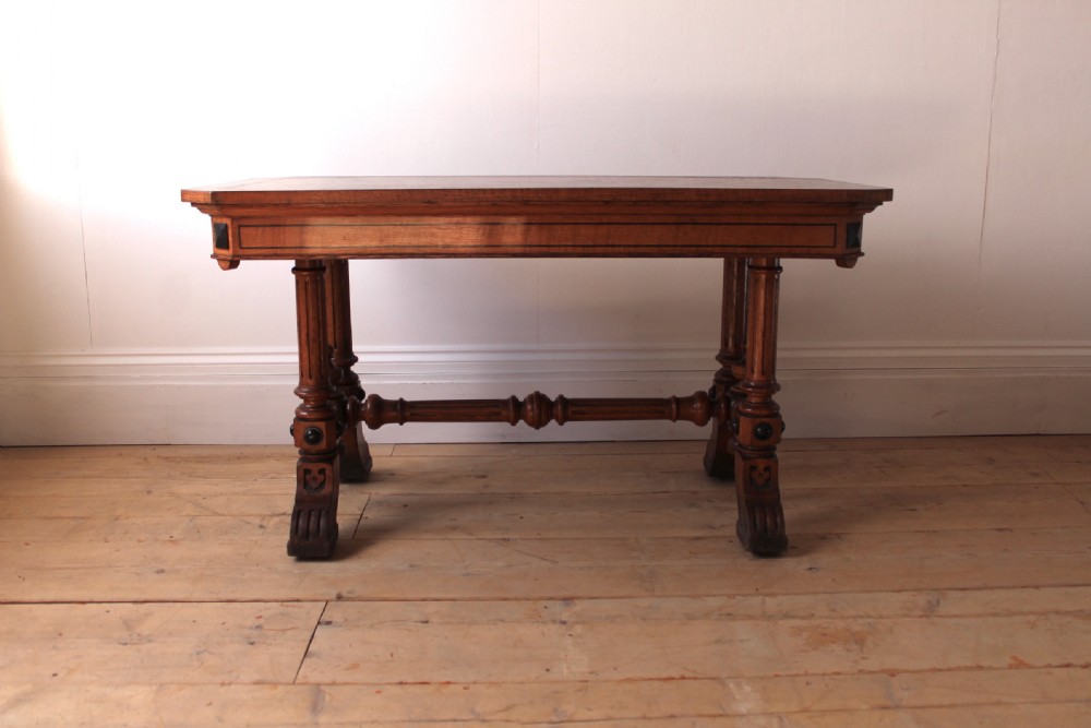 A 19th-century rectangular warm brown walnut centre table featuring inlaid apron details, twin fluted column supports, and a central turned stretcher.