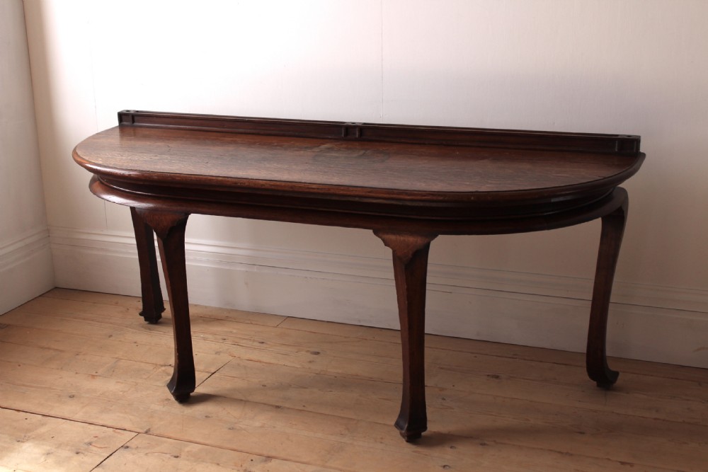 A 19th-century dark wood demi-lune table featuring a semicircular top, a low rear gallery edge, and four shaped legs. View II