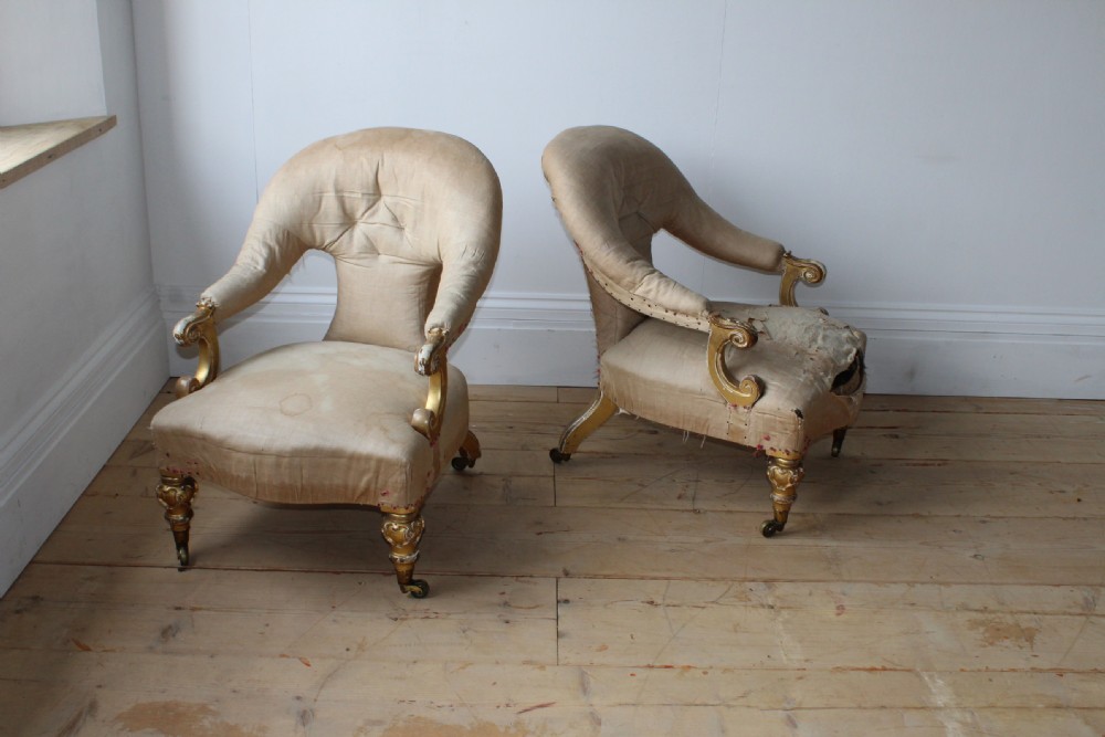 A pair of 19th-century upholstered armchairs with carved giltwood legs on brass castors and cream fabric upholstery. View II