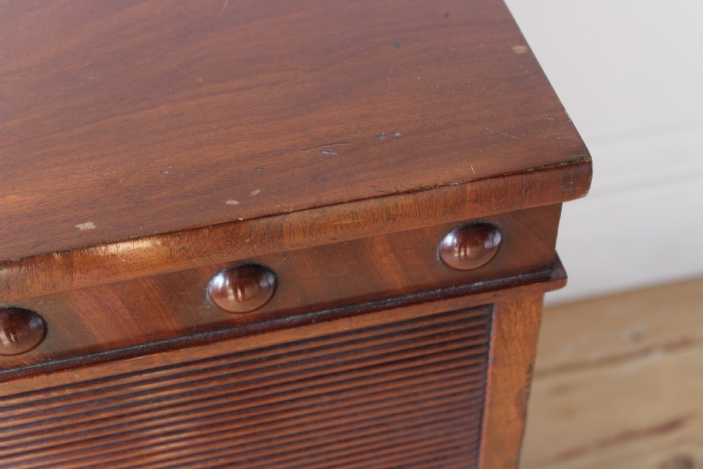 A 19th-century warm mahogany pot cupboard featuring a slatted tambour roll-front shutter door above a lower panelled cabinet on a plinth base. View VI