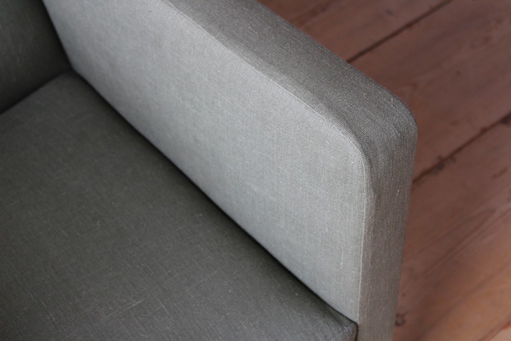 A 19th-century upholstered library armchair in sage green fabric, featuring turned wooden front legs with brass castors. View IV