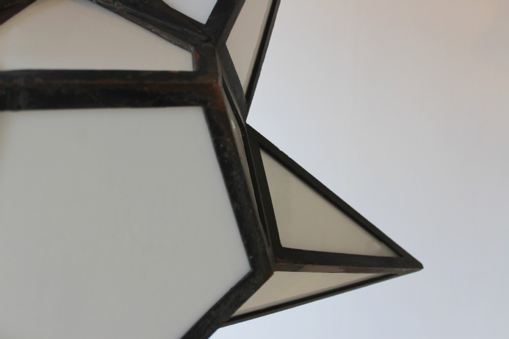 A star-shaped pendant light featuring opaque white glass panels set within a dark soldered metal frame and suspended by a looped top stem. View V