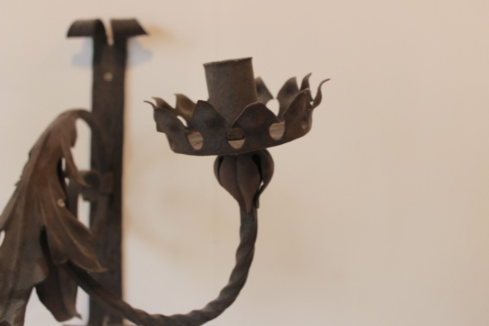 A pair of dark wrought iron Gothic wall lights featuring three twisted branches, coronet-style candle cups, and carved foliate detailing. View IV