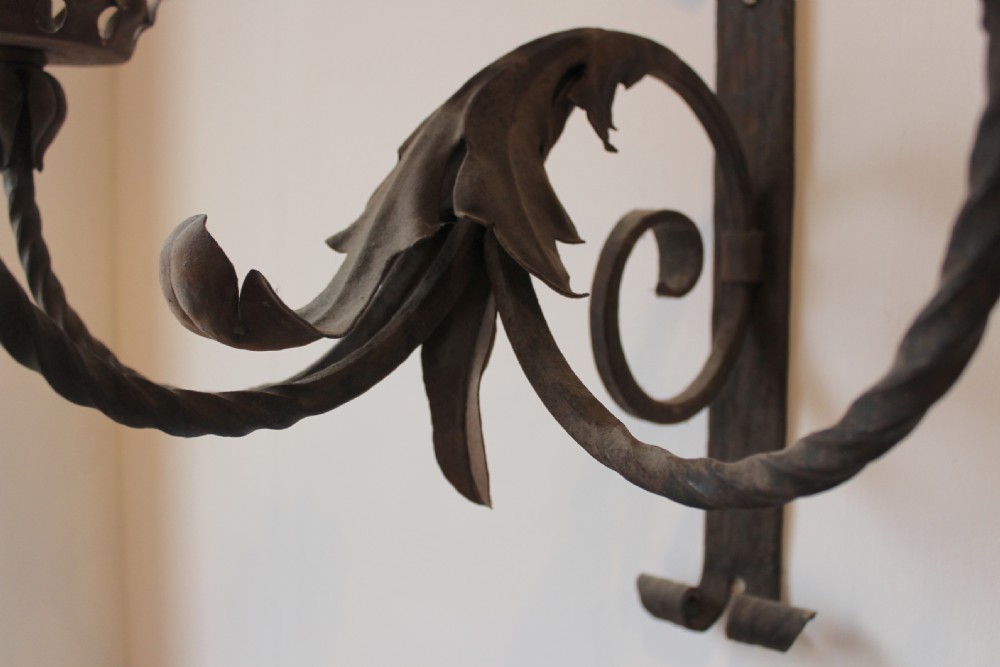 A pair of dark wrought iron Gothic wall lights featuring three twisted branches, coronet-style candle cups, and carved foliate detailing. View V