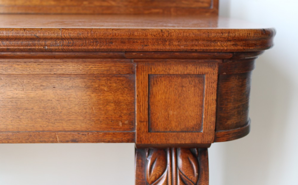 A William IV mahogany console table featuring hand-carved leaf scroll supports terminating in carved paw feet with a raised gallery back. View IV