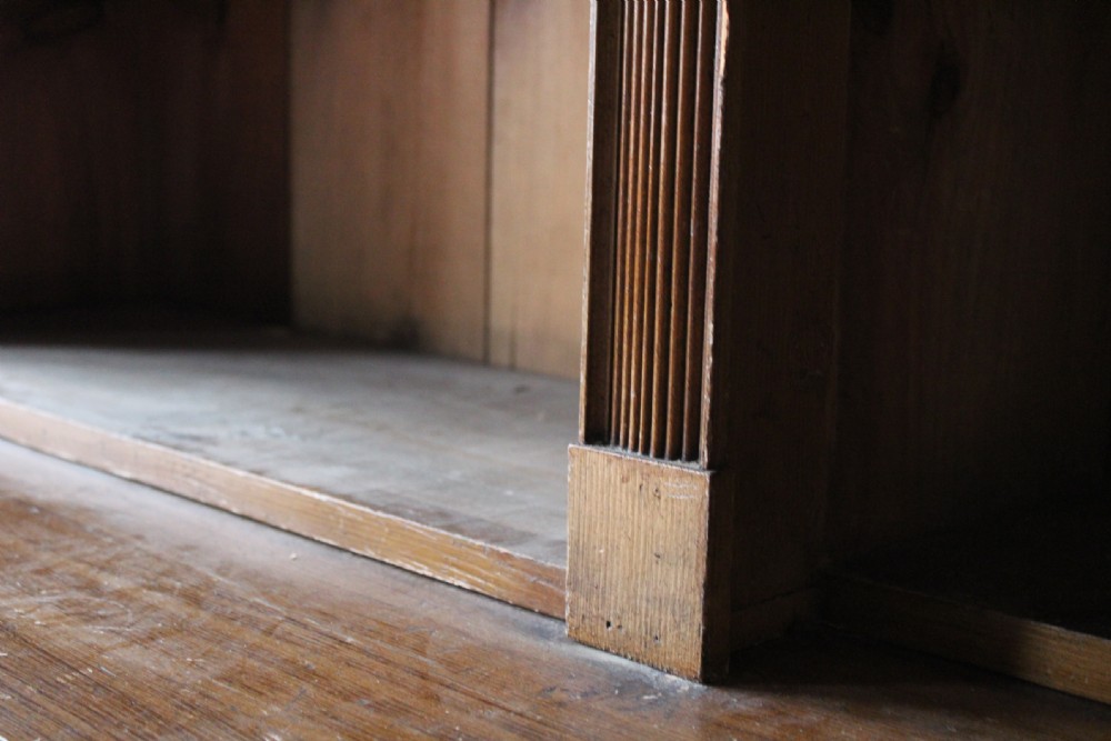 A large nineteenth-century open pine bookcase featuring three upper shelving sections set above three deeper lower compartments. View V