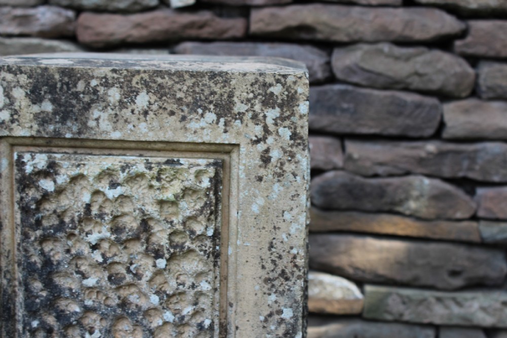 A pair of weathered nineteenth-century carved stone plinths featuring rectangular recessed panels with textured rusticated carving and moulded bases. View II