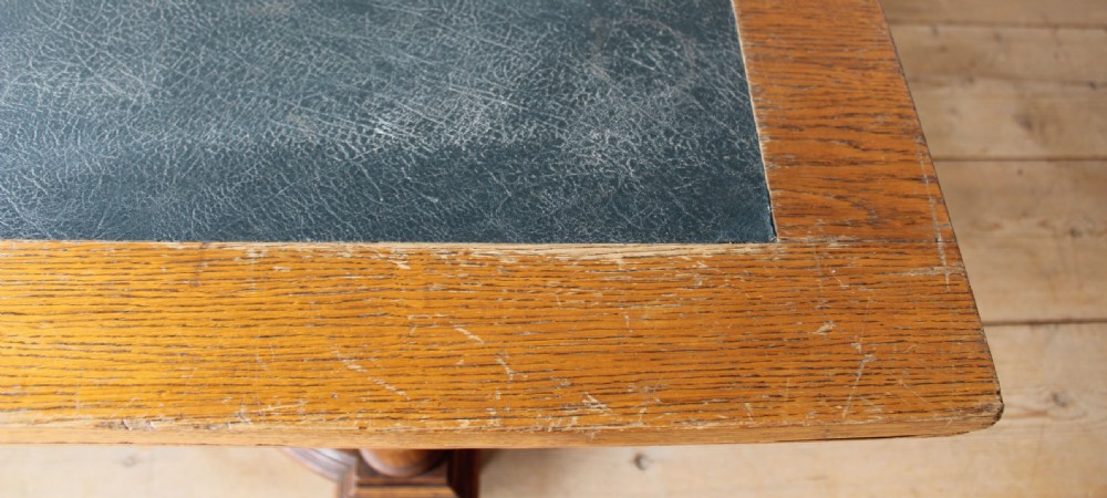 A 19th-century Arts and Crafts oak library table featuring four turned column legs, carved corner brackets, and a curved stretcher base. View III