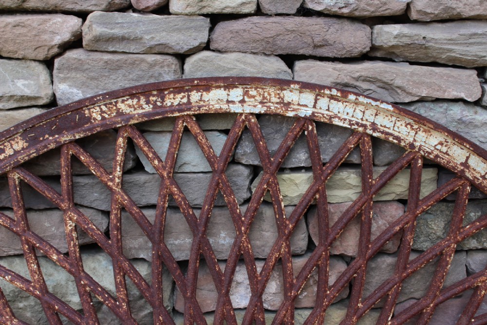 A large circular 19th-century cast iron ceiling rose featuring a radial lattice design with a rust brown patina and remnants of white paint. View III