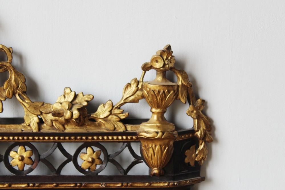 An 18th-century rectangular Neoclassical wall mirror featuring an ebonised frame adorned with carved giltwood festoons, rosettes, and an ornate cresting finial. View V